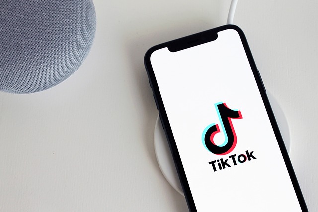An iPhone on a white table shows the TikTok logo on its screen.