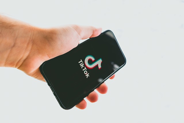 Someone holds a smartphone that displays the TikTok logo.