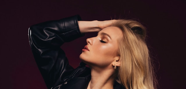 A beauty influencer places her fingers in her hair and poses for a beauty shot.