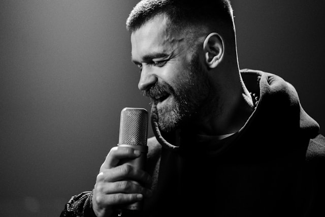 A singer grabs a microphone with his right hand as he sings.