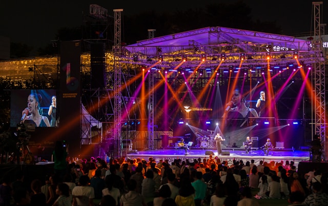Colorful spotlights light up performers on a stage and a big audience.