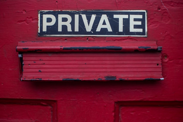 A black and white sign that says “PRIVATE” above a red mailbox.