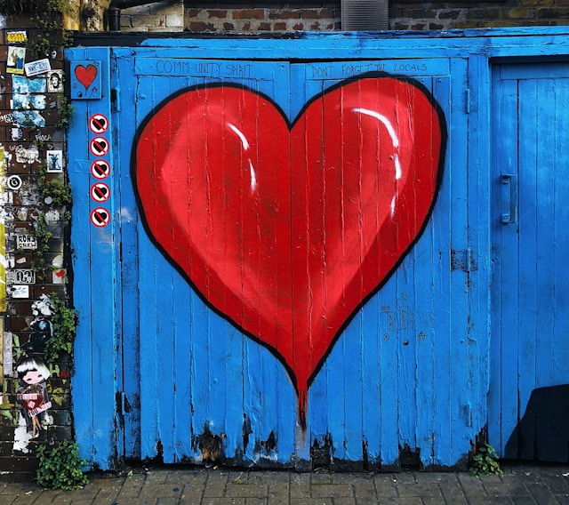 Blue wooden doors with a big, red heart painted on them.