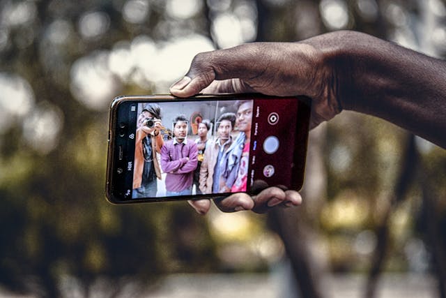 A phone screen shows multiple people in a photo.