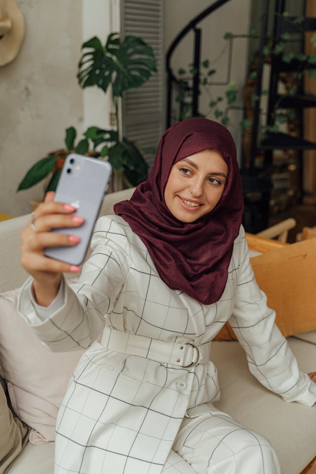A woman with a hijab takes a selfie.