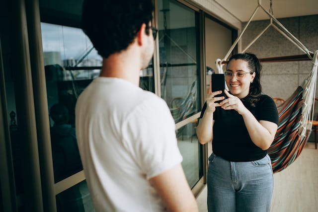 A woman takes a photo of a man.