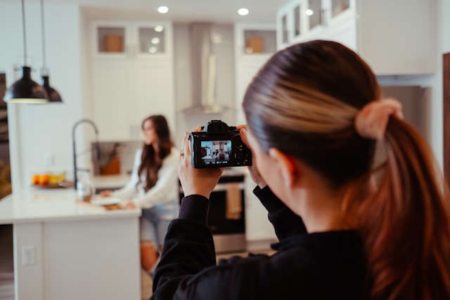 A woman takes a video of a TikTok creator in the kitchen.
