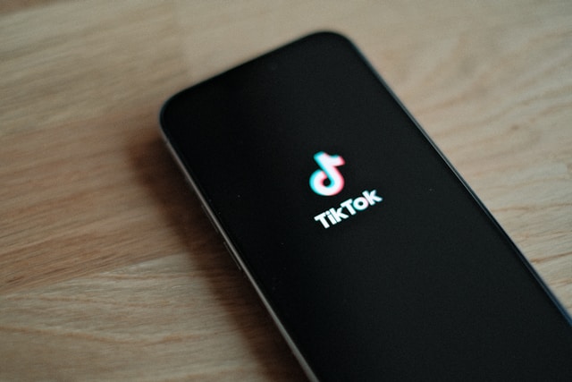 A phone screen displays the TikTok logo on its screen.