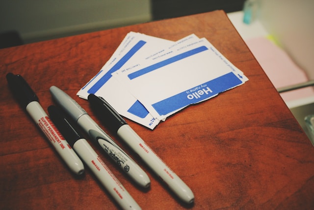 A table with black markers and a stack of blank name tags.
