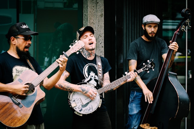 Three street performers play instruments and sing for a crowd.