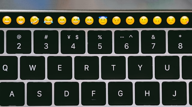 A black keyboard features a row of face emojis at the top.
