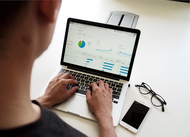 An analyst studies various graphs on his laptop.