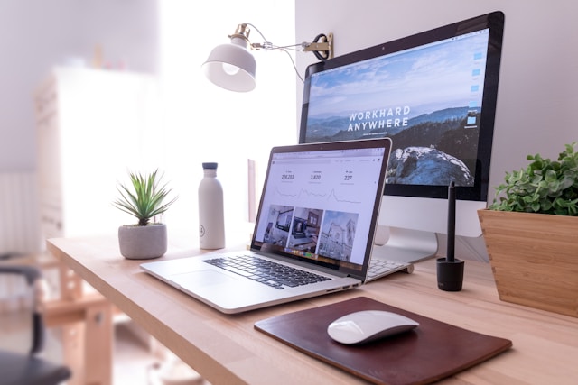 A laptop sits in front of a larger monitor.