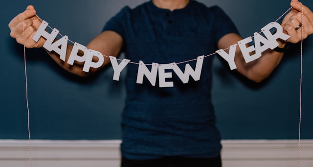 A person holds a “Happy New Year” string decoration.