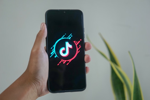 A phone screen displays the TikTok logo as the app loads.