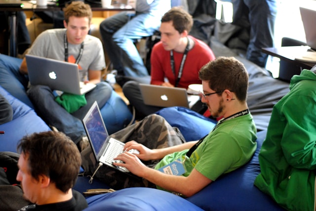 Colleagues sit on bean bags while working on their laptops.