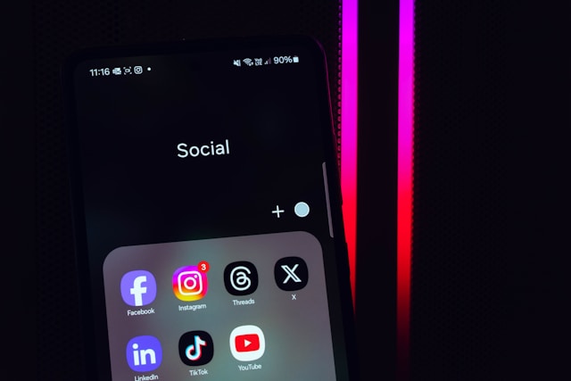 A mobile phone displays several social media apps in an apps folder.