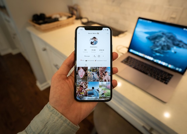 Someone holding a phone with a TikTok profile on it.