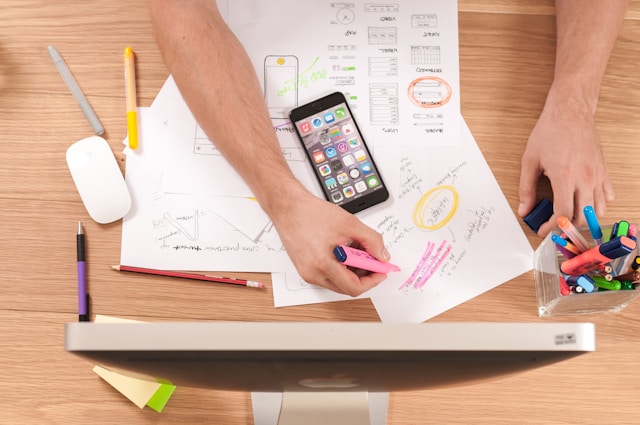 A person sits at a table and makes notes while using highlighters.