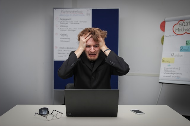 A man looks devastated as he stares at his laptop screen.