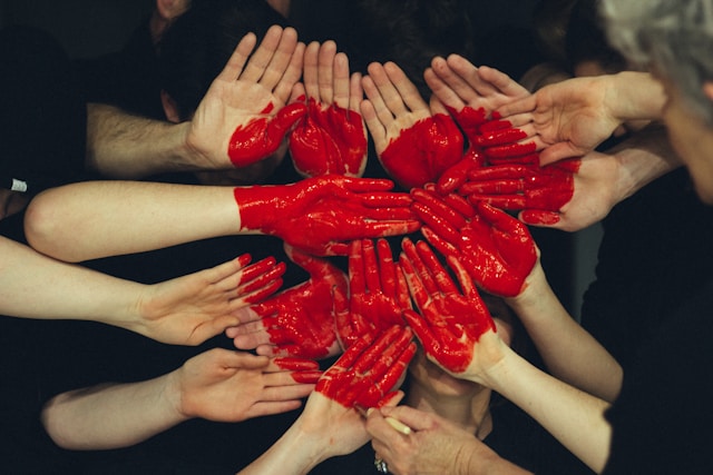 Hands painted red form the shape of a heart.